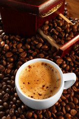 Cup of fresh coffee with beans on table, closeup