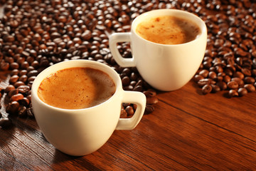 Two cups of fresh coffee with beans on table, closeup