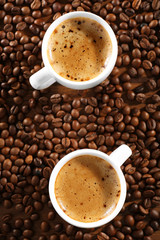 Two cups of fresh coffee with beans on table, closeup