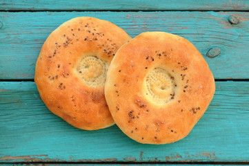 Two round chapatis with sesam seeds on blue wooden table