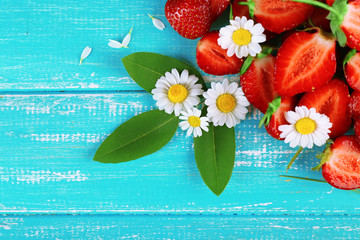 Strawberry with chamomile, leaves and ears on color wooden background