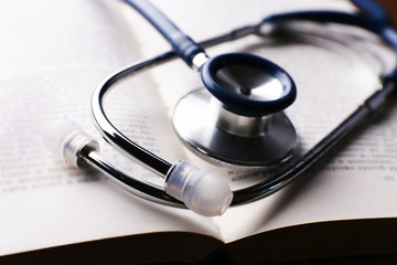Stethoscope on book on wooden table, closeup