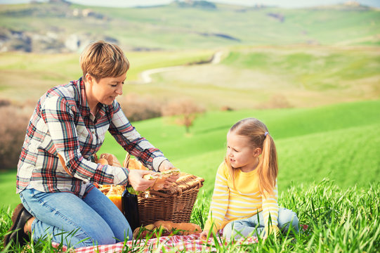 Mother and daughter arranged picnic on the green spring grass in