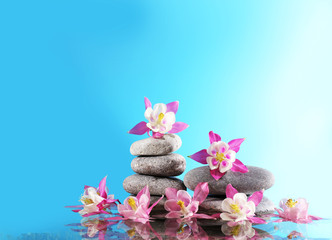 Stack of spa stones with flowers on blue background