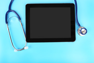 Tablet and stethoscope on blue background