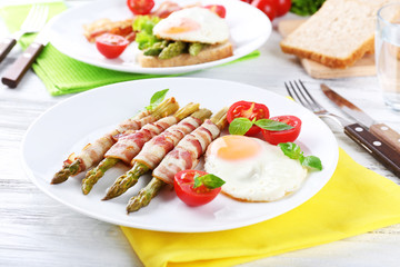 Fototapeta na wymiar Dish of asparagus with bacon and egg in plate on table, closeup