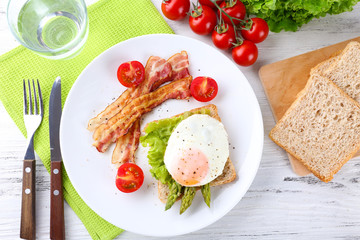 Dish of asparagus with bacon and egg in plate on table, top view