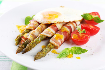 Dish of asparagus with bacon and egg in plate on table, closeup