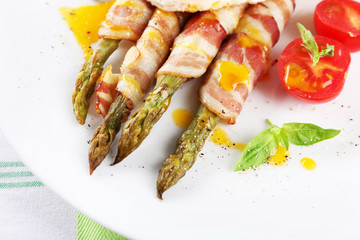 Dish of asparagus and bacon in plate on table, closeup