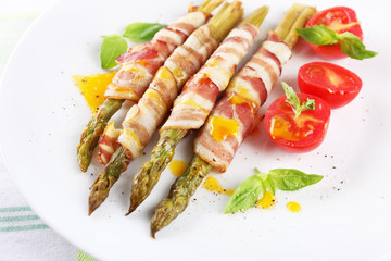Dish of asparagus and bacon in plate on table, closeup