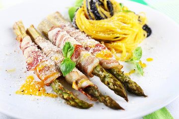 Dish of asparagus, bacon and pasta in plate on table, closeup