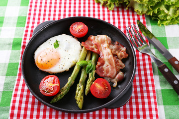 Dish of asparagus with eggs and bacon in pan on table, closeup