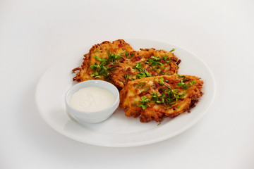 Plate of fried vegeterian potato pancakes with cup of cream