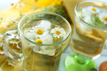 Glasses of chamomile tea with chamomile flowers on color wooden background