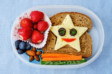 Foto op Plexiglas schoollunchdoos voor kinderen met eten in de vorm van grappige gezichten © nata_vkusidey