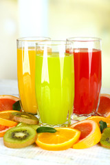 Fototapeta na wymiar Glasses of different juice with fruits and mint on bright background