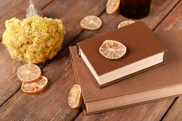 Old books with dry flowers and lemon on wooden background