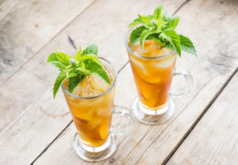 Glass of sweet peach iced tea on the wooden table