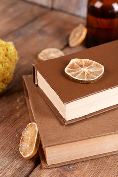Old books with dry flowers and lemon on wooden background