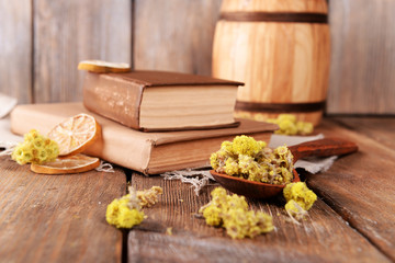 Old books with dry flowers and lemon on table close up