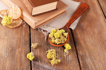 Old books with dry flowers and lemon on table close up