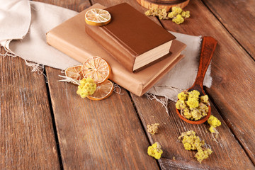 Old books with dry flowers and lemon on table close up