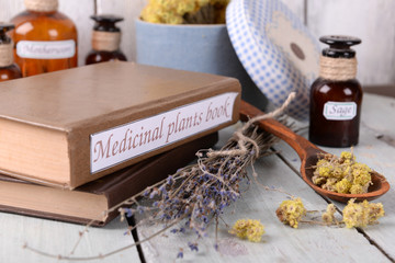 Medicinal plants book with dried herbs on table close up