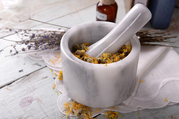Different dried herbs and mortar on table close up