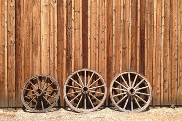 Obraz premium Old wagon wheels lean against a wooden barn