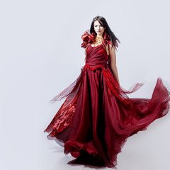 Fashion photo of young magnificent woman in red dress. Studio