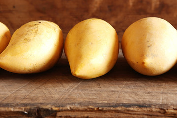 Mangoes in the Row on Wooden Background.