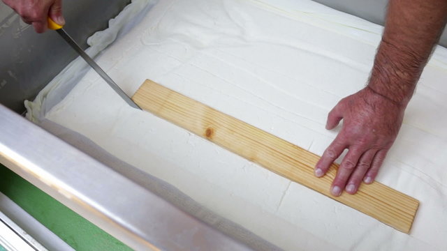 The process of producing tasty traditional white Bulgarian feta cheese at its final stage before packeting. Cutting cubes with a knife.