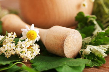 Herbs and flowers with mortar, on wooden table background