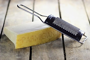 italienischer Hartkäse mit Reibe auf Holzhintergrund