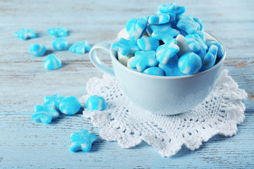 Cup of sweet candies on wooden table, closeup