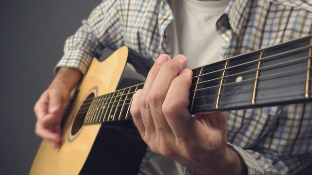 Man playing punk rock riff on acoustic guitar, unplugged blues rock music performance, close up, 4k uhd footage.