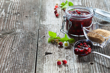 Forest strawberry jam in a jar on rustic wooden background