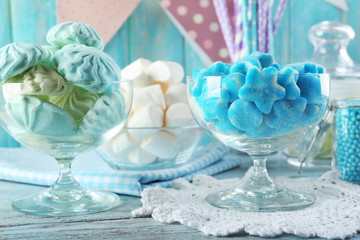 Sweet candies in glassware on wooden table, closeup