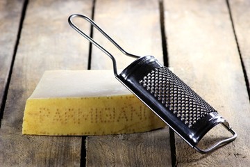 italienischer Hartkäse mit Reibe auf Holzhintergrund