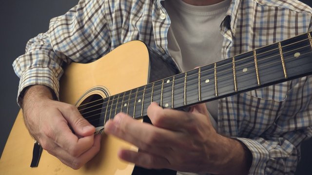 Man playing solo rock tune on acoustic guitar, unplugged blues rock music performance, close up, 4k uhd footage.