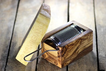 italienischer Hartkäse mit Reibe aus Olivenholz auf Holzhintergrund
