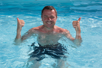 Happy  man in swimming pool holding his thumbs up