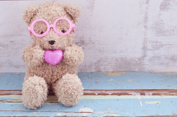 lovely bear doll wearing pink glasses and holding pink heart sha