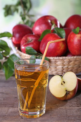 Glass of apple juice with red apples on wooden table, closeup