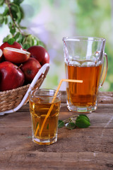 Glass of apple juice with red apples on wooden table on blurred background