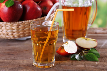 Glass of apple juice with red apples on wooden table, closeup