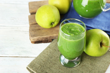 Healthy green smoothie with apples on wooden table, closeup