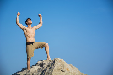 Successful sexy muscular shirtless man with fists raised