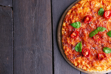 Pizza with basil and cherry tomatoes on wooden table, top view