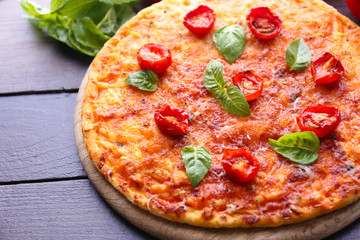 Pizza with basil and cherry tomatoes on wooden table, closeup